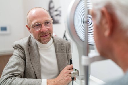 Optometrist smiling at patient during eye exam with Keratograph in foreground