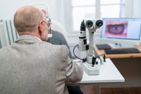 Téléchargez les photos : Optométriste regardant à travers le kératographe lors d'un examen oculaire à la clinique d'ophtalmologie. Photo en gros plan. Concept de santé et de médecine - en image libre de droit