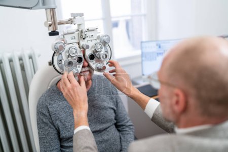 Optometrista ajustando el foropter para la prueba de visión del paciente mayor en la clínica de oftalmología. Fotografía de cerca. Concepto de salud y medicina