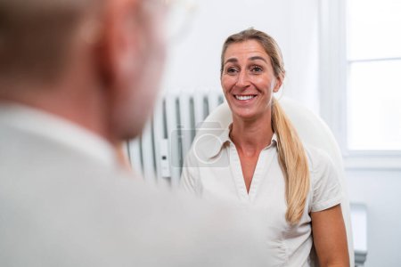 Paciente femenina sonriente en conversación con optometrista durante el examen ocular.