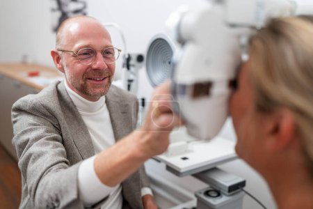 óptico ejecuta una prueba de refracción con un foropter en una paciente femenina en la clínica de oftalmología. Concepto de salud y medicina