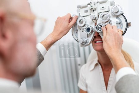 Optometrist conducting a refraction test with a phoropter on a female patient at the ophthalmology clinic. Healthcare and medicine concept