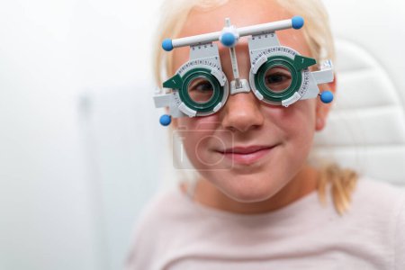 Junges Mädchen mit Proberahmenbrille beim Augenarzt. Augenuntersuchung und Dioptrienmessung in der Augenklinik. Nahaufnahme. Image des Gesundheitswesens und der Medizin