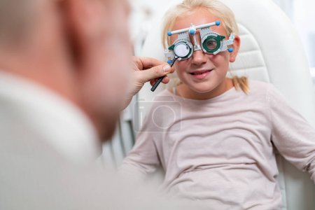 Young girl in a vision test or eye exam for eyesight by doctor, optometrist or ophthalmologist with medical aid.