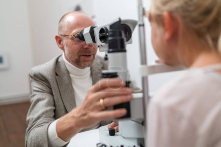 Optometrista que utiliza la máquina de lámpara de hendidura para examinar los ojos de un paciente infantil en la clínica de ojos