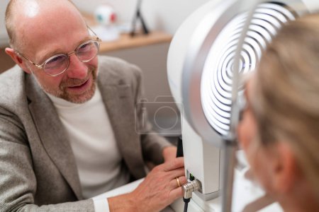 Optometrista involucrándose con un paciente joven y durante un examen ocular con una queratografía en la clínica de oftalmología. Fotografía de cerca. Concepto de salud y medicina