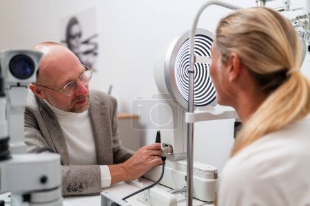 Optometrista usando y ajustando la queratografía para una prueba ocular a una paciente femenina en la clínica de oftalmología. Fotografía de cerca. Concepto de salud y medicina