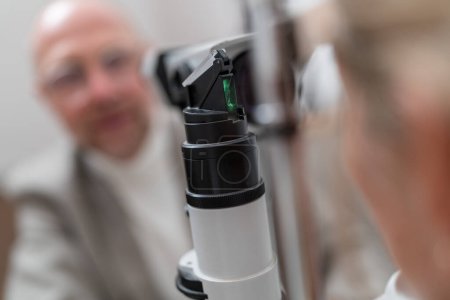 Photo for Optometry equipment slit lamp in focus with patient and optometrist blurred in background - Royalty Free Image