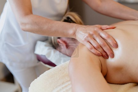 Nahaufnahme einer Massagetherapeutin, die in einem Wellness-Schönheitssalon an der Schulter eines Kunden arbeitet