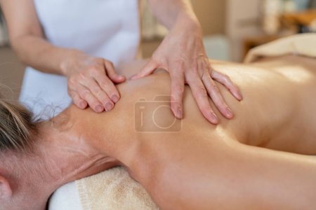 Close-up view of a massage therapist applying pressure to a female client's back