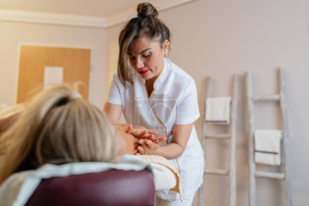 Konzentrierte Massagetherapeutin, die in einem Wellnessbereich am Rücken der Klientin arbeitet. Schönheitssalon Wellness Hotel Konzept Bild