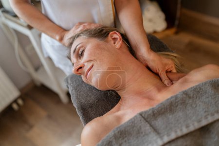 Therapeutin bietet einer entspannten Kundin in einem Wellnesshotel eine Nackenmassage an