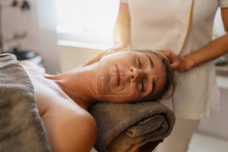 Therapeutin bietet einer entspannten Klientin in einem Wellness-Hotel eine Nackenmassage an