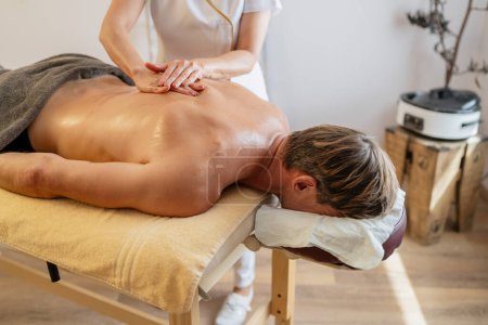 Foto de Cliente masculino recibiendo un masaje de espalda de un terapeuta en un moderno hotel spa - Imagen libre de derechos