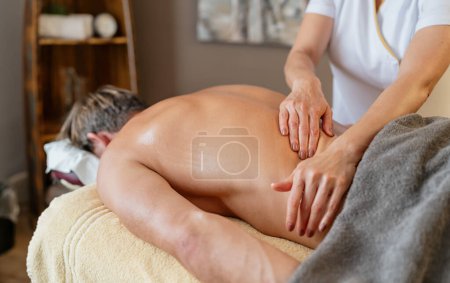 Téléchargez les photos : Massothérapeute effectuant un massage du dos sur le client masculin dans le spa. Wellness Hotel Concept image - en image libre de droit