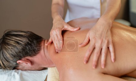 Nahaufnahme eines Massagetherapeuten, der an der Schulter und am Rücken eines Klienten arbeitet