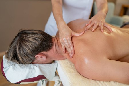 Nahaufnahme einer Massagetherapeutin, die in einem Schönheitssalon an der Schulter und am Rücken einer Klientin arbeitet