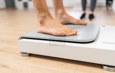 Close-up of bare feet stepping onto a modern body composition scale in a fitness or medical setting during Inbody test