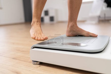 pieds nus marchant sur une échelle de composition corporelle moderne dans un cadre de fitness ou médical lors d'un test intra-corporel