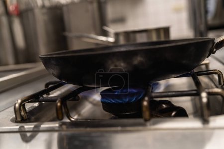 Foto de Sartén con llamas de fuego azul de una estufa de cocina profesional. Cocina de gas con llamas de gas propano. Industrial Lujo hotel cocina recursos y economía concepto imagen. - Imagen libre de derechos