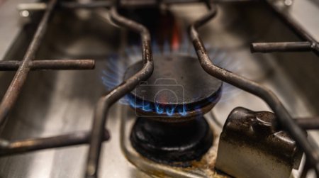 Closeup shot of blue fire flames from a professional kitchen stove top. Gas cooker with burning flames of propane gas. Industrial Luxury hotel cooking resources and economy concept image.