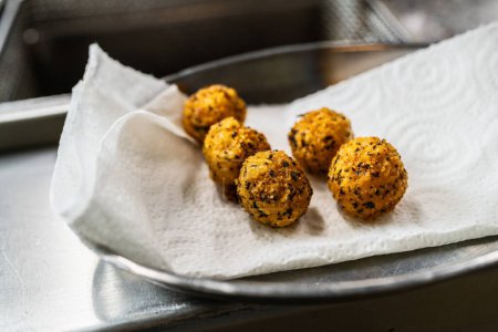 Luxuriöse Vorspeise aus gebratenen Kartoffelbällchen mit Kräutern in der Küche eines Restaurants. Food Fotografie Konzeptbild