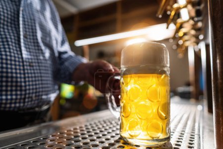Barkeeper serviert Bier im Becher im Biergarten oder auf dem Oktoberfest, München, Deutschland