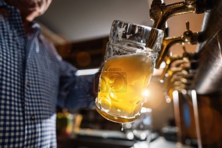 Deutscher Barkeeper schenkt Bier im Biergarten oder auf dem Oktoberfest ein, München, Deutschland