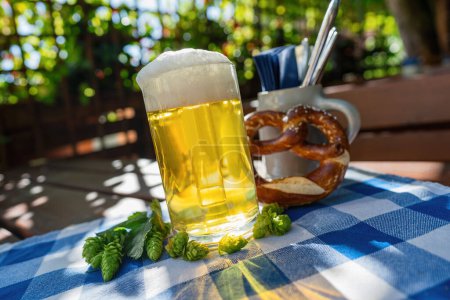 Beer mug with fresh pretzel or brezen and hops at Biergarten or Oktoberfest, Munich, Germany