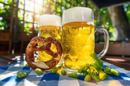 Foto de Tazas de cerveza con pretzel fresco o brezen y lúpulo en Oktoberfest, Munich, Alemania - Imagen libre de derechos