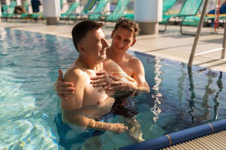 Séance de thérapie de réadaptation dans une piscine avec un formateur aidant un patient heureux. Aqua fitness concept image.