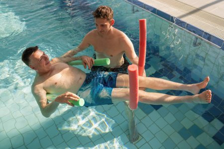 Ejercicio de rehabilitación acuática con el paciente usando fideos de piscina como soporte