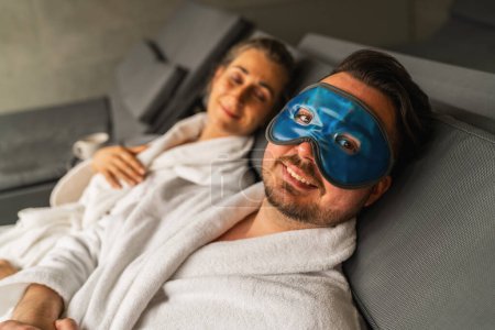 Foto de Pareja relajante en el spa, hombre con máscara de enfriamiento de gel azul, mujer de fondo - Imagen libre de derechos