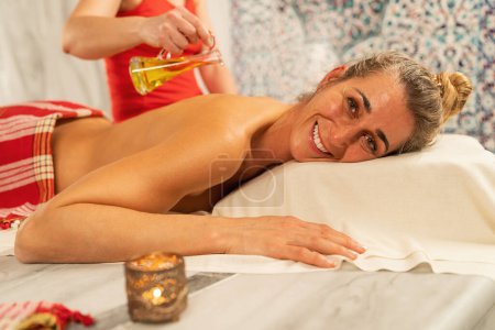 Photo for Happy woman lying on a hot stone in hamam, sauna - Royalty Free Image