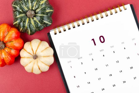 Téléchargez les photos : Calendrier bureau : Octobre est le mois pour l'organisateur de planifier et date limite avec une petite citrouille sur un fond rouge. - en image libre de droit