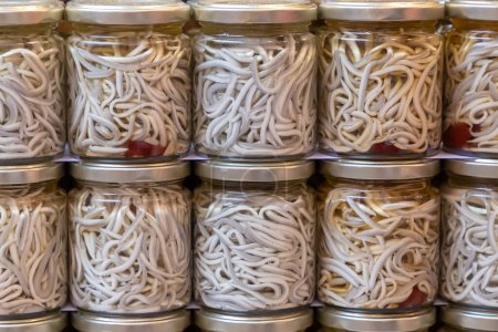 Photo for Close up in horizontal view of several glass jars with preserved baby eels. food preservation concept - Royalty Free Image