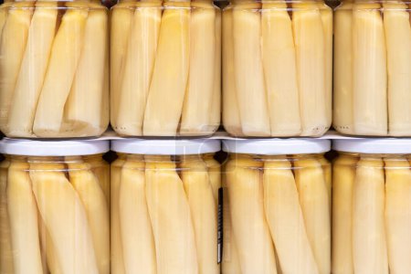 close up in horizontal view of several glass jar with preserved white large asparagus. food preservation concept