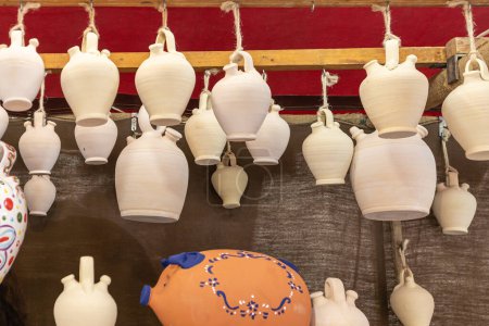 Photo for Close up in horizontal view of several white botijos of clay hanging from the ceiling. botijo is a drinking jug with spout - Royalty Free Image