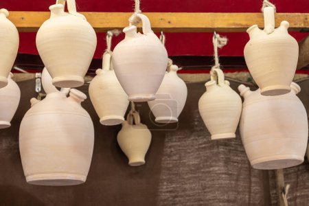 Photo for Close up in horizontal view of several white botijos of clay hanging from the ceiling. botijo is a drinking jug with spout - Royalty Free Image