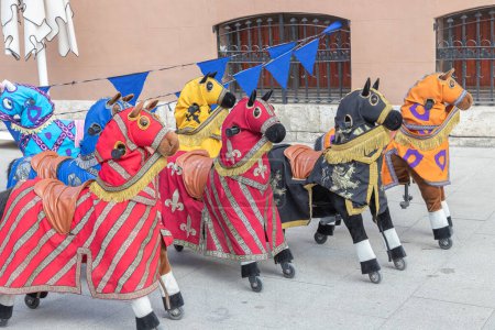 Téléchargez les photos : Vue horizontale d'une attraction amusante pour les enfants avec des petits chevaux à roues vêtus de couvertures de cheval médiévales - en image libre de droit