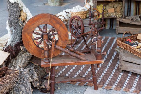 Horizontale Ansicht eines Outdoor-Ladens aus mit natürlichen Farbstoffen gefärbten Wollen und einem antiken Pedal-Holzspinnrad im Vordergrund