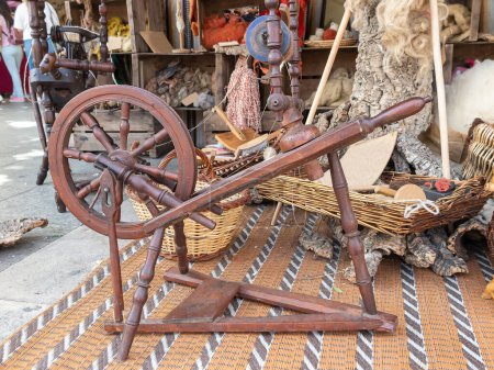 Téléchargez les photos : Vue horizontale d'un atelier extérieur de laines teintes avec des colorants naturels et une roue à pédale antique en bois au premier plan - en image libre de droit