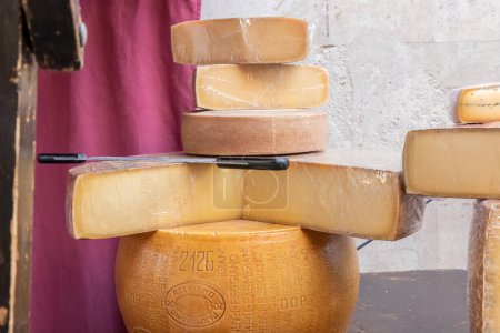 Photo for ALCALA DE HENARES, MADRID, SPAIN - OCTOBER 9, 2022: large portions of different types of cheese stacked on a wooden table of a outdoor stall during celebaration of a medieval festival in the city of alcala de henares - Royalty Free Image