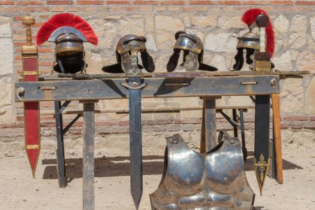 Photo for Outdoor scene in horizontal view of an exhibitor with helmets, swords an cuirass of soldiers from the time of ancient roman empire. trip to the past - Royalty Free Image