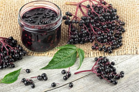 Photo for Fresh ripe black elderberries, elderberry syrup and leaves of elderberry on rustic wooden board. Alternative medicine and lifestyle. - Royalty Free Image