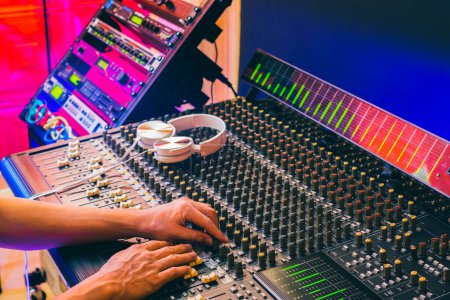 Téléchargez les photos : Ingénieur du son mains mélangeant la musique sur console de mixage audio dans le home studio - en image libre de droit