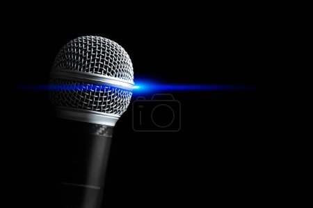 Foto de Primer micrófono dinámico con luz de concierto azul, aislado en negro. Canto, grabación, radiodifusión, concepto del habla - Imagen libre de derechos