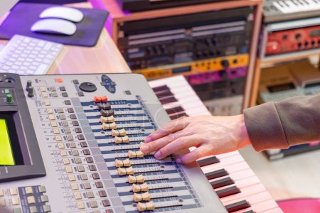 male sound engineer hand adjust fader on digital mixing console in recording studio