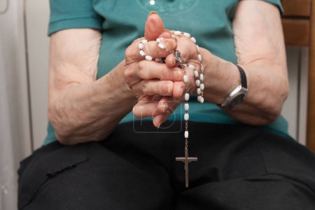 Hände einer älteren treuen Frau, die einen Rosenkranz in der Hand hält und betet. Großmutter. Katholisch. Christian