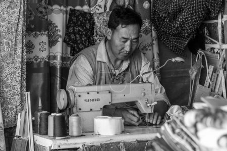 Photo for GYANTSE, TIBET, CHINA - AUGUST, 21 2018: Unidentified tibetan man with sewing machine in Gyantse, Gyantse Country, Shigatse, Tibet - Royalty Free Image